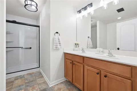 a bathroom with double vanity sinks and a shower