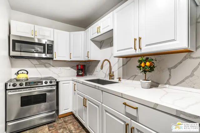 a kitchen with stainless steel appliances granite countertop a sink a stove and cabinets