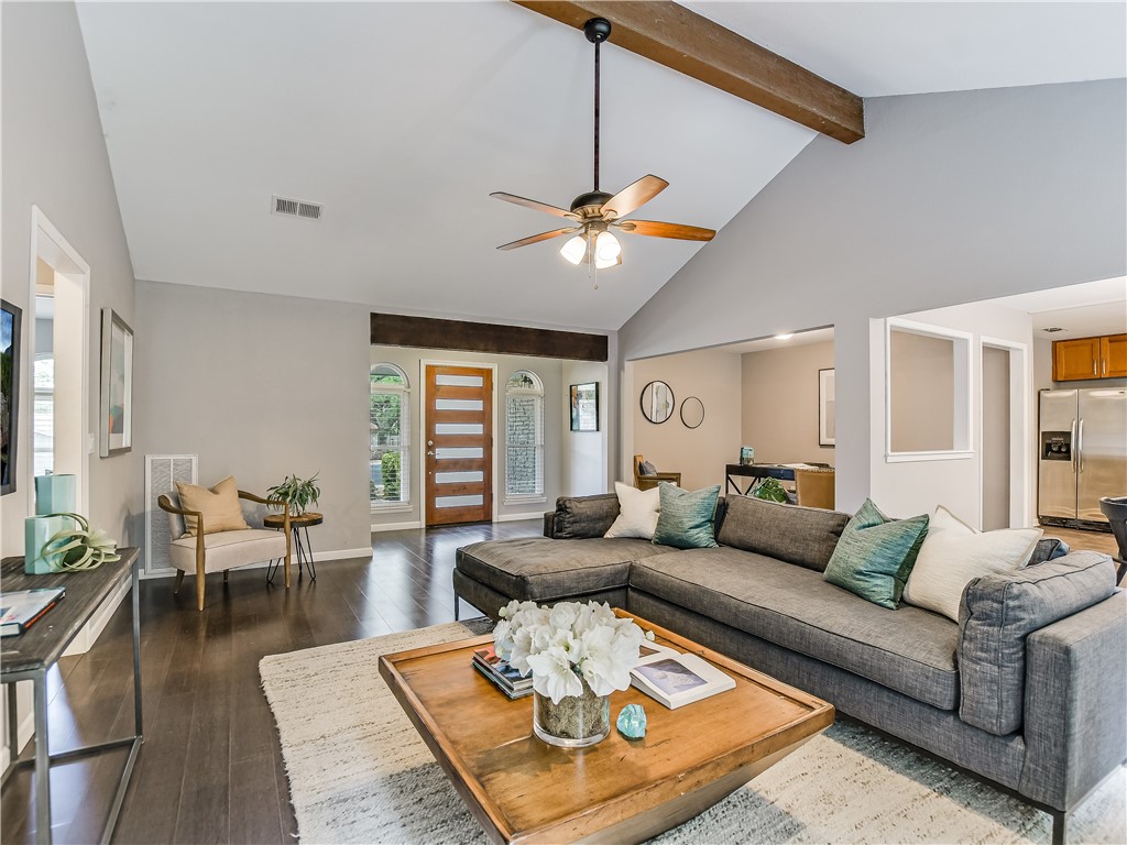 The spacious living room boasts a high vaulted ceiling with a stunning rustic wood beam.