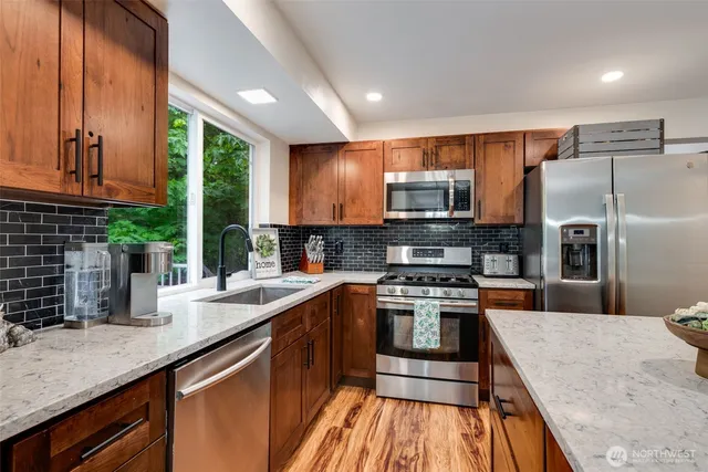 a kitchen with stainless steel appliances granite countertop a sink a stove and a refrigerator