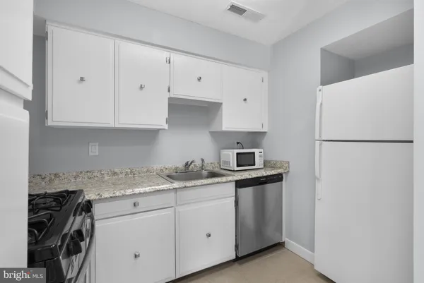 a kitchen with granite countertop white cabinets and stainless steel appliances