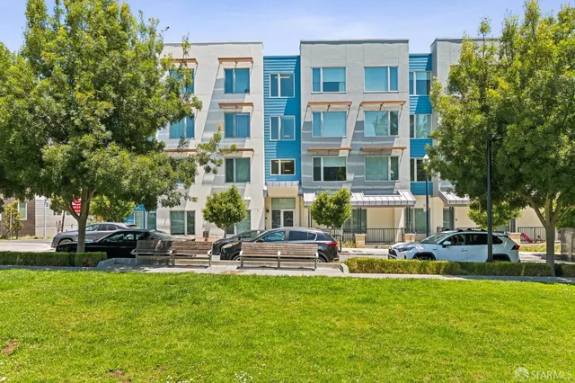 a front view of a building with garden and trees