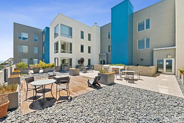 a roof deck with table and chairs couches and potted plants