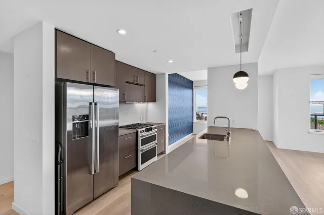 a kitchen with stainless steel appliances granite countertop a refrigerator a sink a stove and a sink with wooden floor