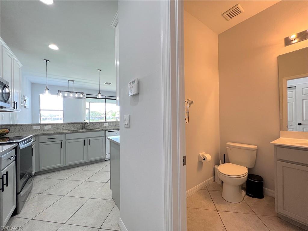 14776 Sutherland Avenue, Unit 416 Naples, FL 34119 - Photo 22 of 50 a bathroom with a granite countertop sink a toilet a mirror and a bathtub