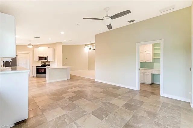 a view of an empty room and chandelier fan