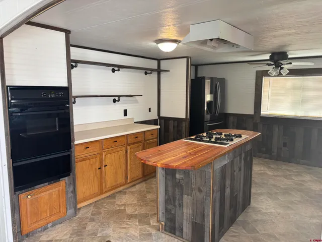 a kitchen with granite countertop a refrigerator and a stove top oven