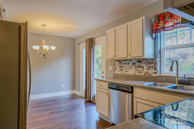 a kitchen with stainless steel appliances granite countertop a refrigerator a sink dishwasher and wooden cabinets with wooden floor