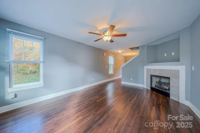 a view of an empty room with wooden floor a fireplace and a window