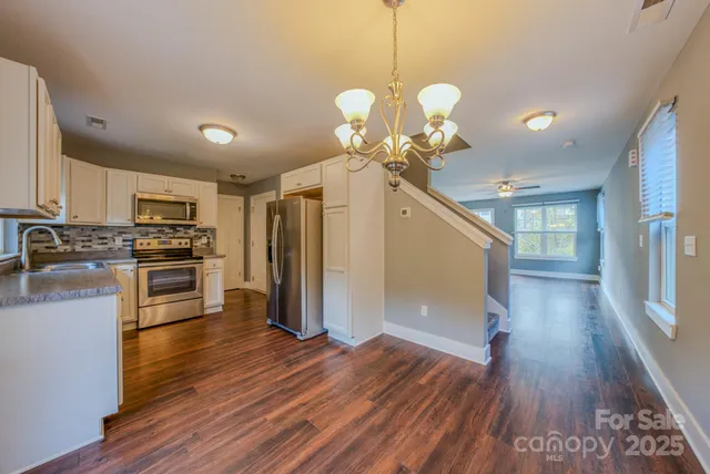 a view of a kitchen center island wooden floor and stainless steel appliances