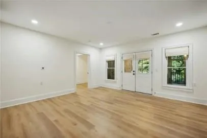 a view of an empty room with wooden floor and windows