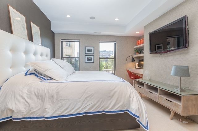 a spacious bedroom with a bed and a flat screen tv