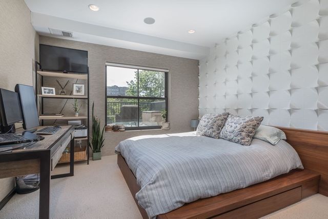 a bedroom with a bed a computer on the desk and a book shelf