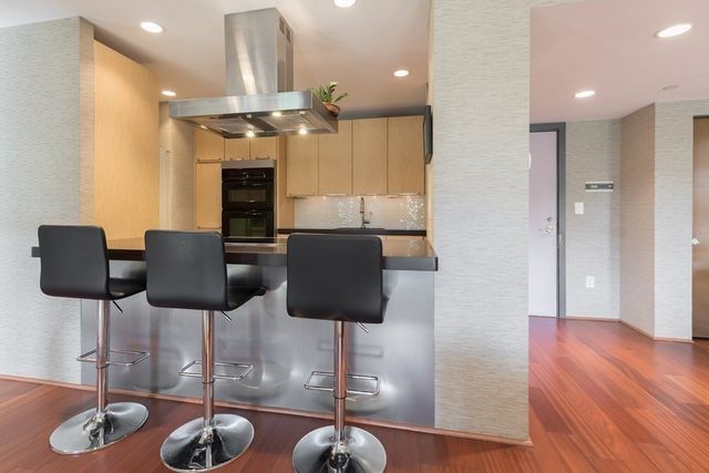 a kitchen with stainless steel appliances granite countertop a refrigerator a stove a microwave oven a dining table and chairs with wooden floor