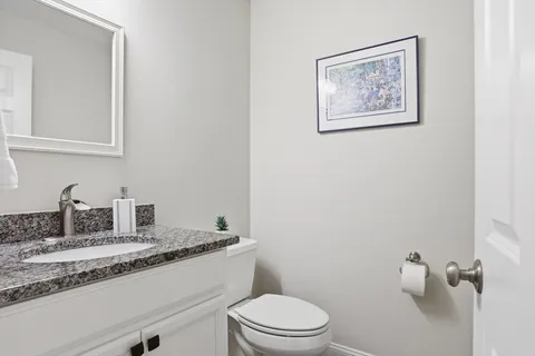 a bathroom with a granite countertop toilet sink and mirror