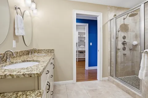 a bathroom with a granite countertop sink a mirror and shower
