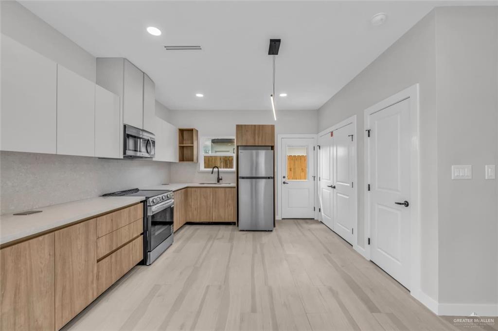 11509 North 25th Street, Unit A McAllen, TX 78504 - Photo 4 of 17 Kitchen with modern cabinets, stainless steel appliances, light wood-style flooring, backsplash, and pendant lighting