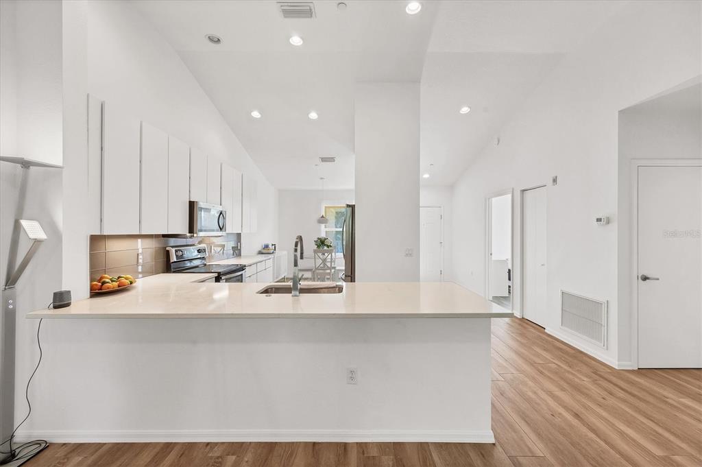 7131 Boca Grove Place, Unit 203 Lakewood Ranch, FL 34202 - Photo 8 of 50 a large white kitchen with wooden floor