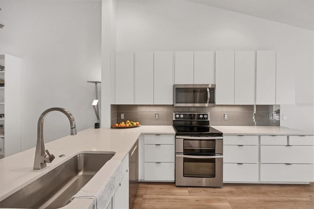 7131 Boca Grove Place, Unit 203 Lakewood Ranch, FL 34202 - Photo 9 of 50 a kitchen with stainless steel appliances granite countertop a stove a sink and white cabinets