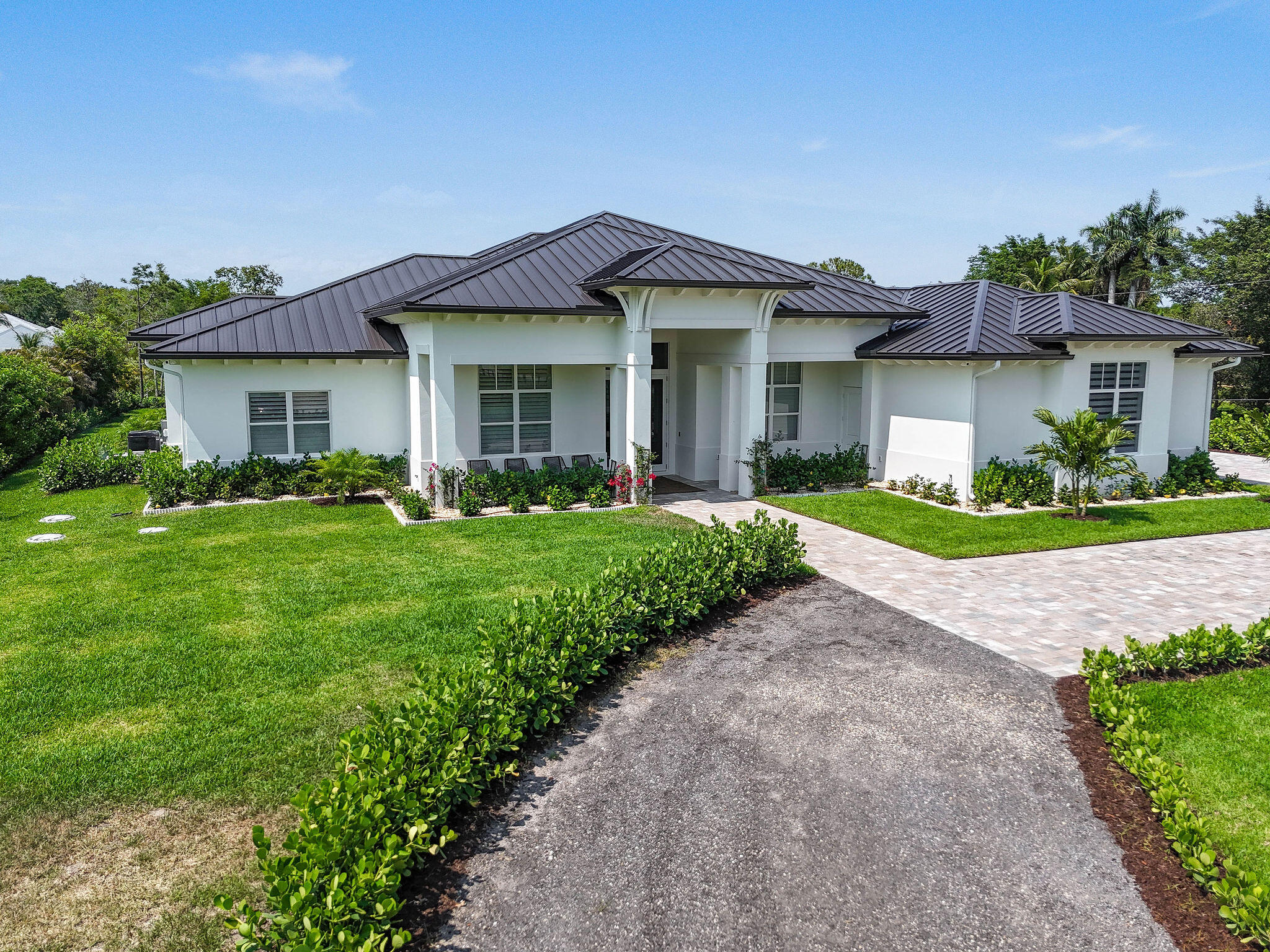 9105 Whippoorwill Trail Jupiter, FL 33478 - Photo 3 of 60 a front view of a house with a yard and potted plants