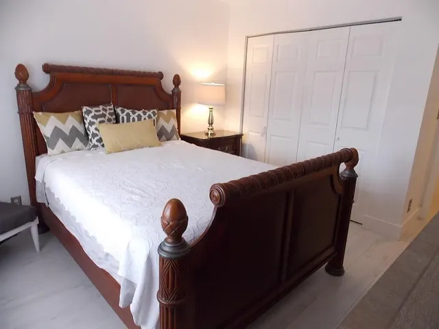 a bed sitting in a bedroom next to a window and a larger closet