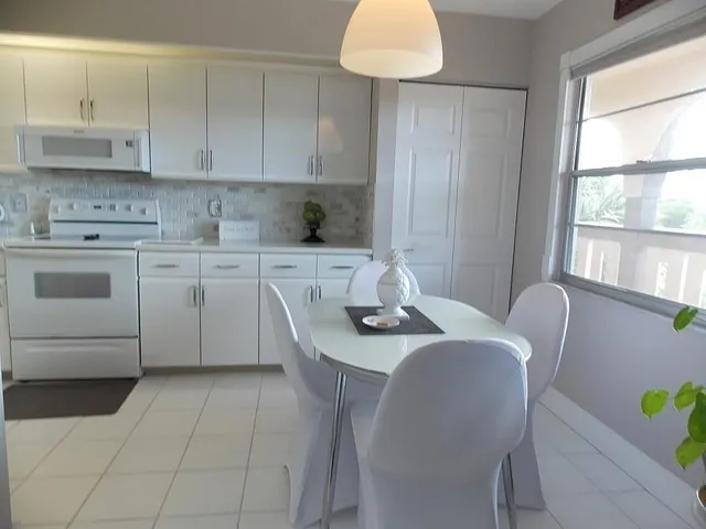 a kitchen with stainless steel appliances granite countertop a sink a stove a dining table and chairs next to a window