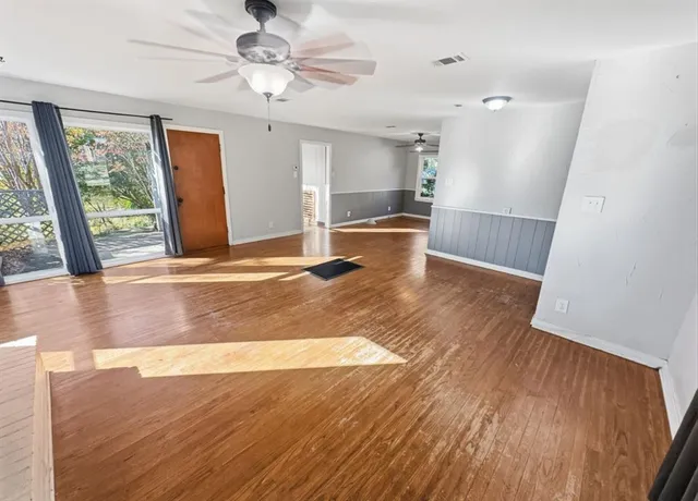 a view of empty room with wooden floor and fan