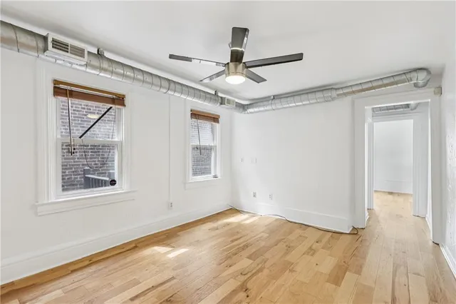 a view of empty room with wooden floor and fan