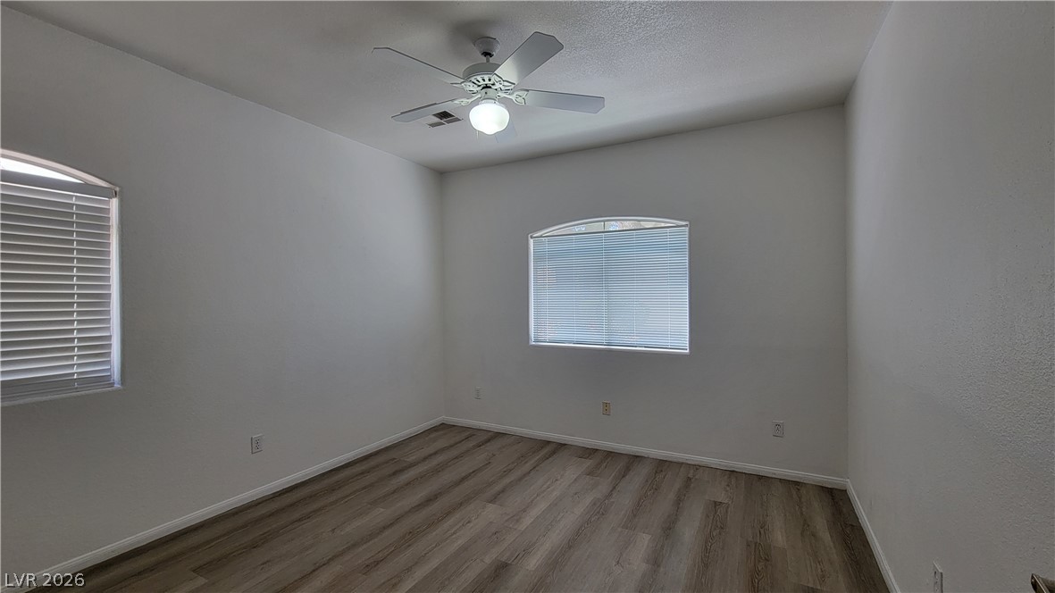 3320 South Fort Apache Road, Unit 111 Las Vegas, NV 89117 - Photo 8 of 12 A well-lit bedroom with modern wood-look flooring and a ceiling fan for comfort.