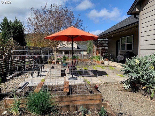 598 Oak Valley Loop Winchester, OR 97495 - Photo 17 of 21 a view of a patio with chairs and a table and chairs under an umbrella