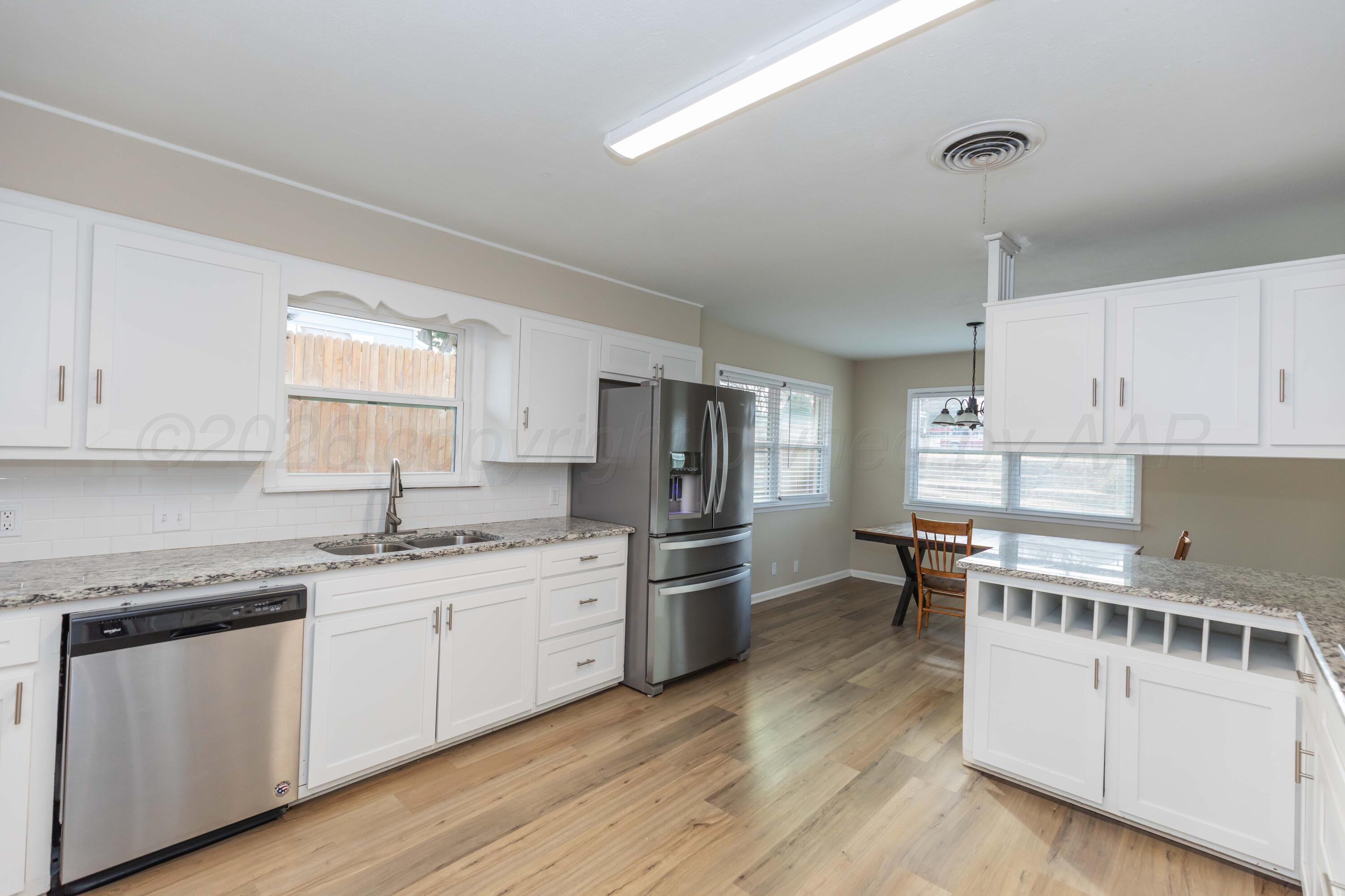 105 Smith Street Borger, TX 79007 - Photo 8 of 26 a kitchen with stainless steel appliances a stove top oven a sink a refrigerator white cabinets and wooden floor