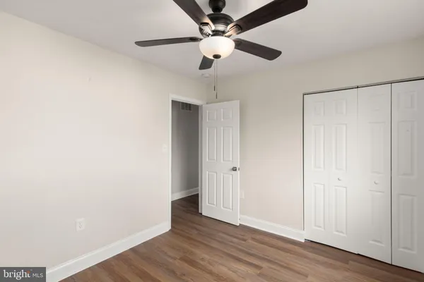 an empty room with wooden floor fan and windows