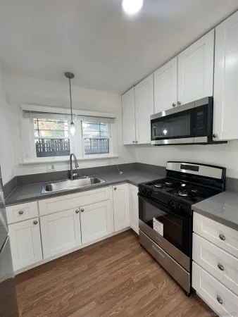 a kitchen with stainless steel appliances white cabinets granite counter tops and a wooden floors