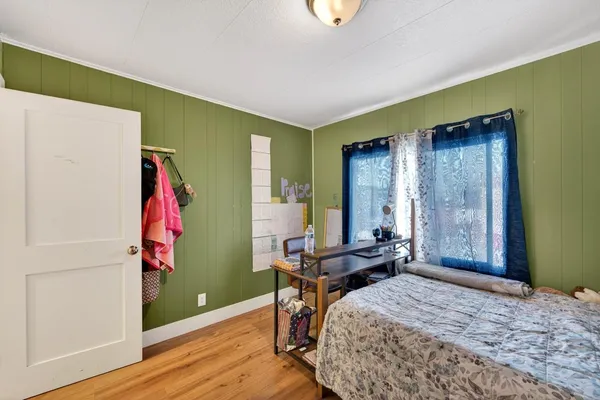 a bedroom with a bed and a bookshelf with wooden floor