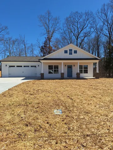 a view of house with a yard and tree in front of it