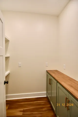a view of an empty room with wooden floor and a ceiling fan