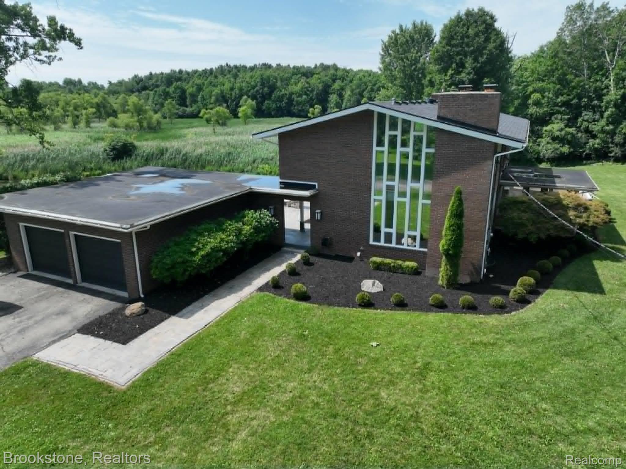 4140 South Henderson Road Davison, MI 48423 - Photo 1 of 98 Brick exterior with a prominent vertical window array, two-car garage, manicured lawn, and mature landscaping