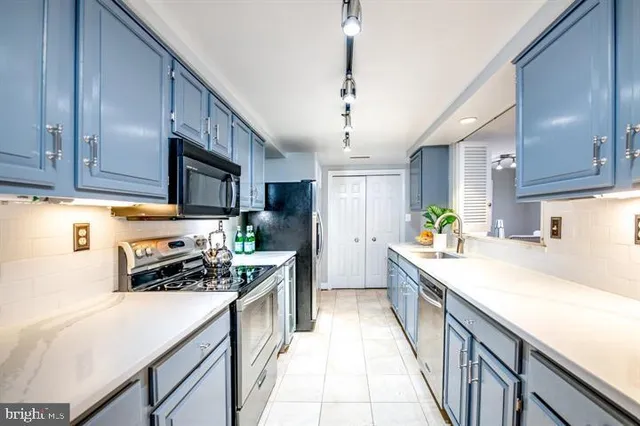 a kitchen with stainless steel appliances kitchen island granite countertop a sink stove cabinets and refrigerator