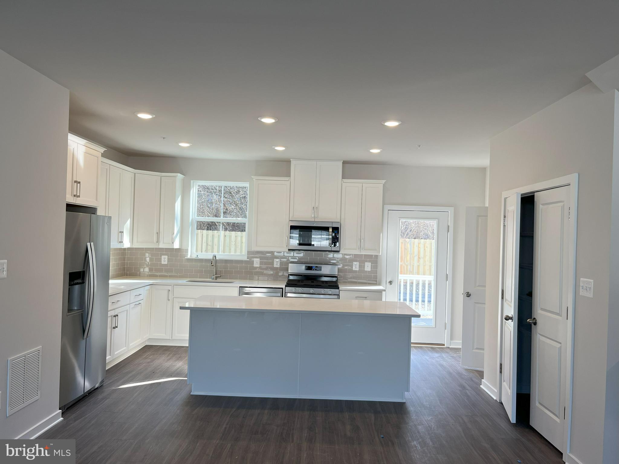 a kitchen with stainless steel appliances granite countertop a stove top oven a refrigerator and a granite counter tops with wooden floors