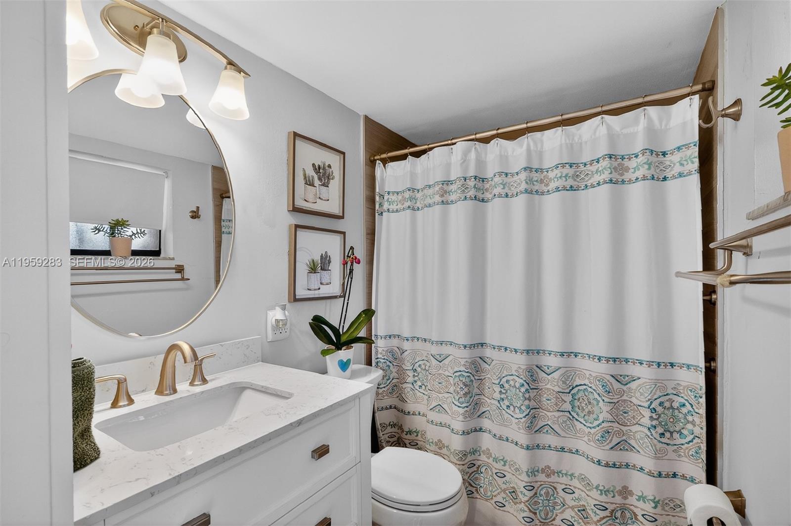 8540 Southwest 133rd Avenue Road, Unit 112 Miami, FL 33183 - Photo 16 of 23 a bathroom with a granite countertop sink toilet a mirror and shower curtain