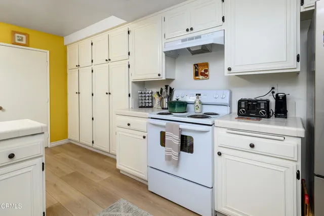 a kitchen with white cabinets and white appliances