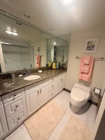 a spacious bathroom with a toilet sink double vanity and mirror