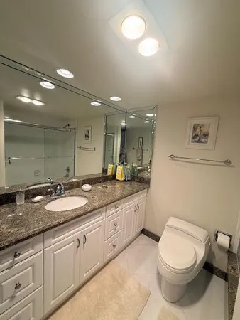 a bathroom with a granite countertop toilet sink and mirror