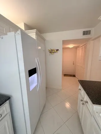 a view of a kitchen with refrigerator and white cabinets