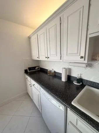 a kitchen with granite countertop a sink a stove and cabinets