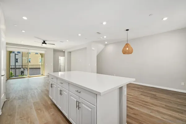 a large white kitchen with a sink and wooden floor