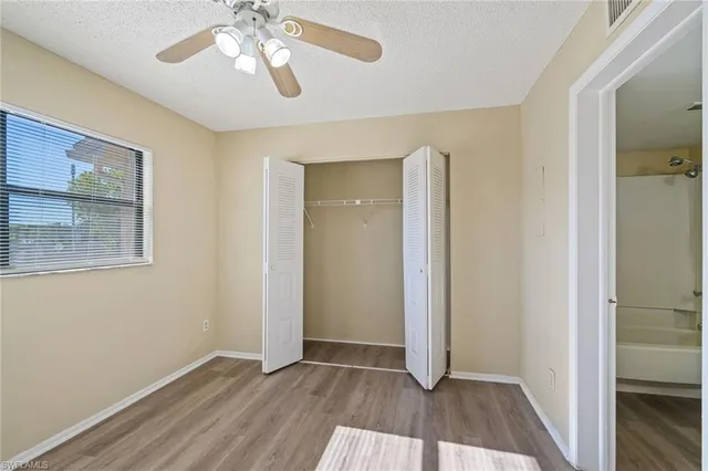 a view of an empty room with wooden floor and a bathroom