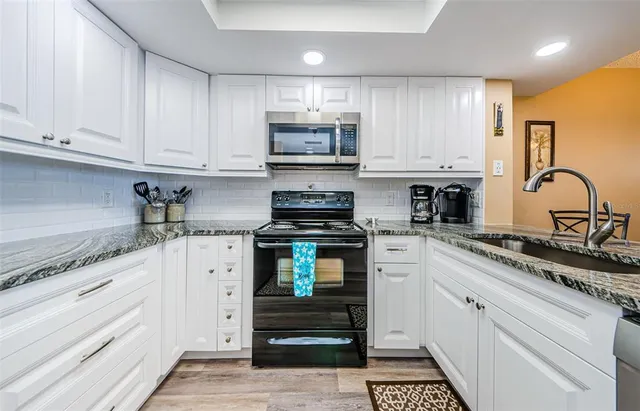 a kitchen with stainless steel appliances kitchen island granite countertop a stove a sink and a microwave