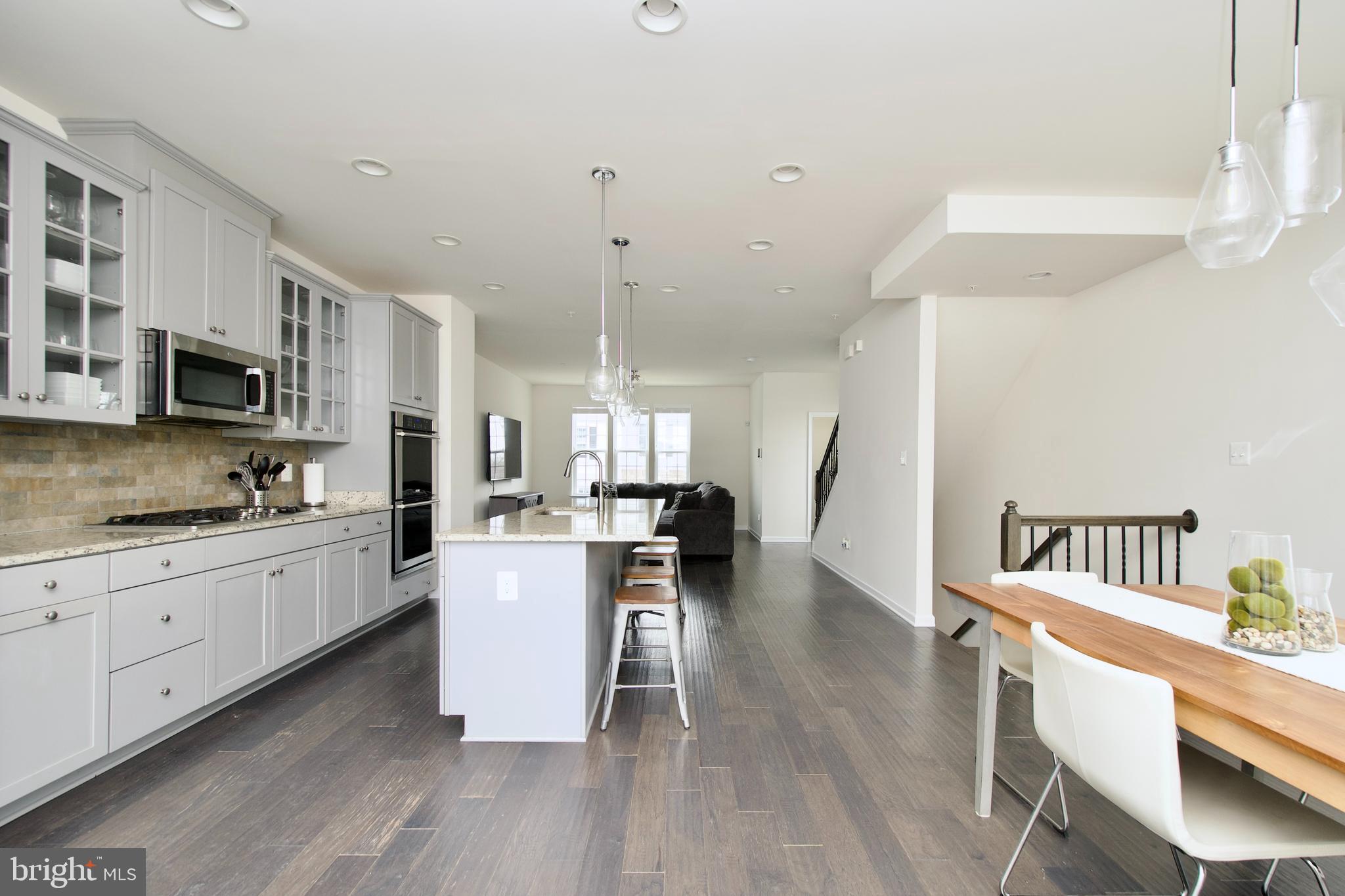 2900 Pinebrook Road Landover, MD 20785 - Photo 17 of 46 a kitchen with microwave a stove a sink dishwasher a dining table and chairs with wooden floor