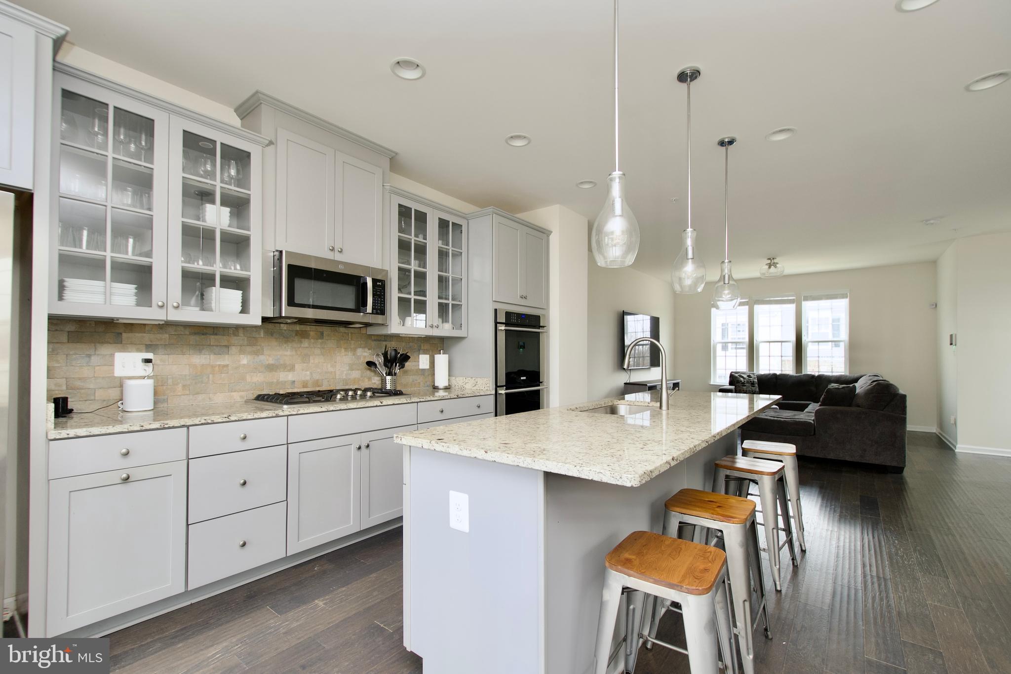 2900 Pinebrook Road Landover, MD 20785 - Photo 9 of 46 a open kitchen with stainless steel appliances granite countertop a stove top oven a sink a dining table and chairs with wooden floor